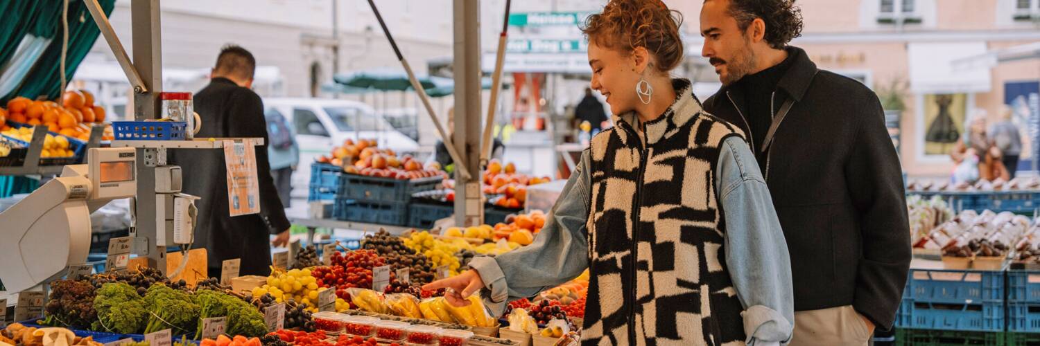 Two people looking at fresh produce at the Grünmarkt (a market in Salzburg) | © TSG Tourismus Salzburg GmbH / M. Kohlmayr