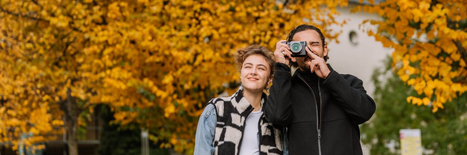 Two people sightseeing in Salzburg with autumn trees in the background. | © TSG Tourismus Salzburg GmbH, Kohlmayr