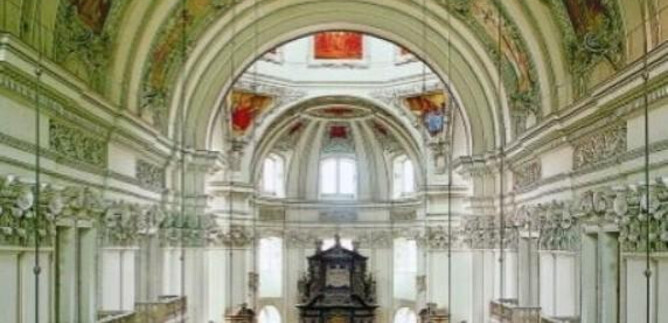 Una chiesa impressionante con un soffitto alto e affreschi artistici. La vista interna mostra una disposizione simmetrica di banchi e un altar eccessivo. | © Kunst & Kultur
