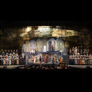 An impressive theater performance featuring many actors in historical costumes. The backdrop displays a dramatic landscape with rocks and buildings. | © Franz Neumayr