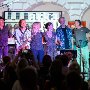 A lively stage with a band performing. The musicians are gathered together and presenting their show to an audience. | © Harald Gaukel