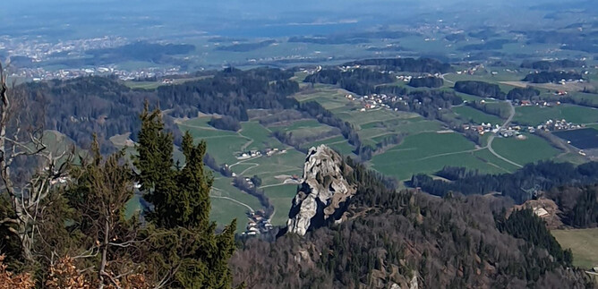 Eine malerische Landschaft mit grünen Feldern und Bergen. Im Vordergrund ist ein auffälliger Felsen zu sehen. | © Sylvia Wienerroither