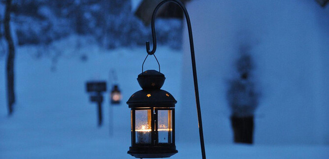 Eine schöne Laterne hängt in der kalten, verschneiten Landschaft. Die Dunkelheit wird von ihrem warmen Licht erhellt. | © Salzburger Freilchtmuseum