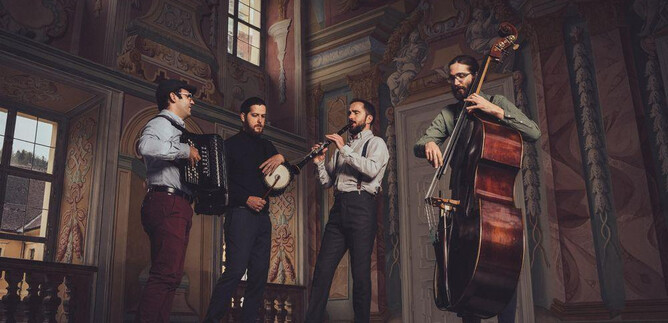 Quattro musicisti suonano in una sala storica. Hanno strumenti diversi come fisarmonica, banjo, flauto e contrabbasso. | © Reithofer Media