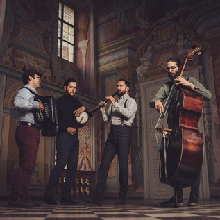 Cuatro músicos tocan en un espacio histórico. Tienen diferentes instrumentos como acordeón, banjo, flauta y contrabajo. | © Reithofer Media