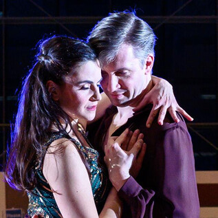 A couple dances closely embraced on a dance floor. The atmosphere is elegant and romantic, with soft lighting in the background. | © SLT / Tobias Witzgall