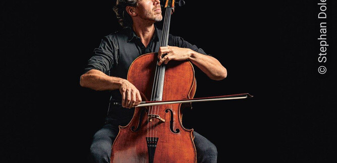 Ein Musiker spielt Cello in einem dramatischen Licht. Der Fokus liegt auf seiner konzentrierten Haltung und dem Instrument. | © Stephan Doleschal