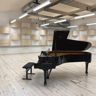 Des bottes noirs reposent sur une table avec un clavier et une souris d'ordinateur. De nombreux câbles sont visibles. | © Haus der Philharmonie