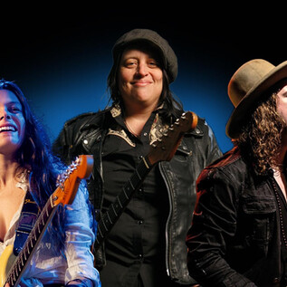 Három zenész áll a színpadon, mindegyikük egy elektromos gitárral. A légkör élénk és zenei, ideális a Blues Caravan 2026-hoz. | © Rockhouse Salzburg