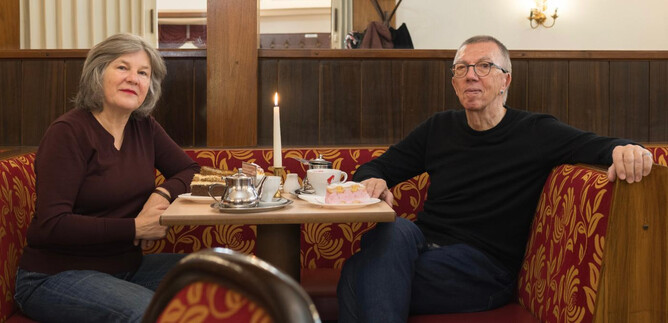 Ein Paar sitzt an einem Tisch in einem gemütlichen Café. Auf dem Tisch stehen Kuchen, eine Kerze und Tassen mit Getränken. | © Wolfgang Lienbacher