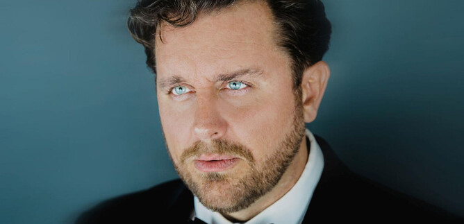 Un uomo in un elegante completo con un papillon nero. Ha un'espressione seria e guarda pensieroso lontano. | © Marco Borelli