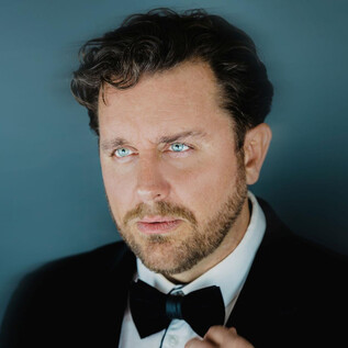 A well-dressed man in a suit with a bow tie. He looks thoughtfully into the distance with an intense gaze. | © Marco Borelli