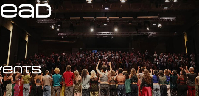 Eine große Menschenmenge steht auf einer Bühne und schaut in Richtung Publikum. Die Atmosphäre ist festlich und einladend. | © www.sead.at