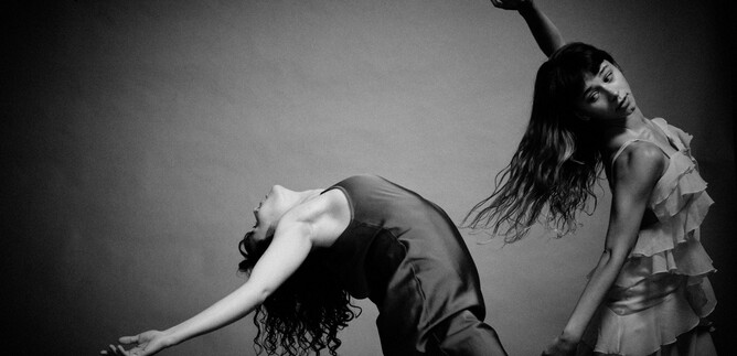 Two dancers in elegant dresses pose in an artistic black-and-white composition. Their movements display dynamism and grace. | © Chris Rogl