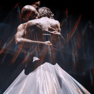 A couple dances intimately in a dramatic play of light. Their bodies are tightly entwined as they assume an elegant pose. | © Anna Ulyanova