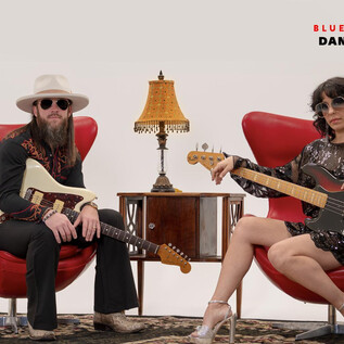 Una banda de rock está sentada en sillones rojos frente a un fondo minimalista. Los músicos llevan gafas de sol y tocan diferentes instrumentos. | © Rockhouse Salzburg