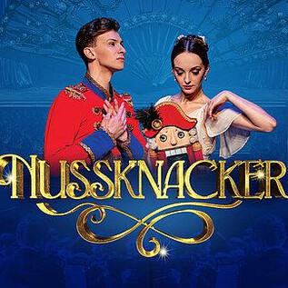 Dwaj tancerze w świątecznych strojach stoją na pierwszym planie. W tle widać świąteczną atmosferę z niebieskimi tonami i żyrandolami, a tytuł "Dziadek do orzechów" jest wyraźnie umieszczony. | © Ovation Events GmbH