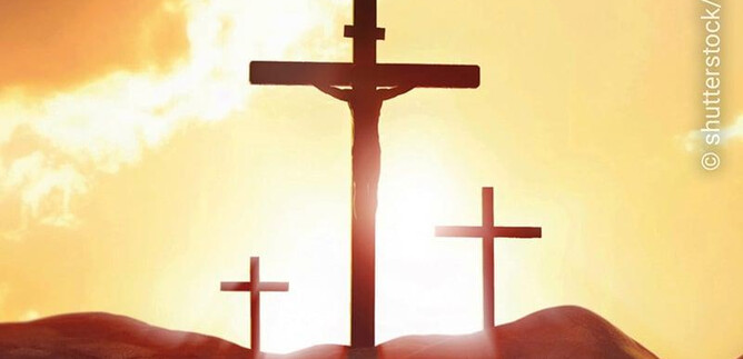 Tři kříže stojí v popředí, siluetované proti zářivému západu slunce. Scéna přenáší duchovní a zamyšlenou atmosféru. | © shutterstock/artin1