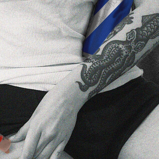 Egy személy injektál magának valamit a combjába. A személy karján részletes tetoválás látható, és a jelenet monokróm színpalettával rendelkezik, néhány színes akcentussal. | © Calixto María Schmutter