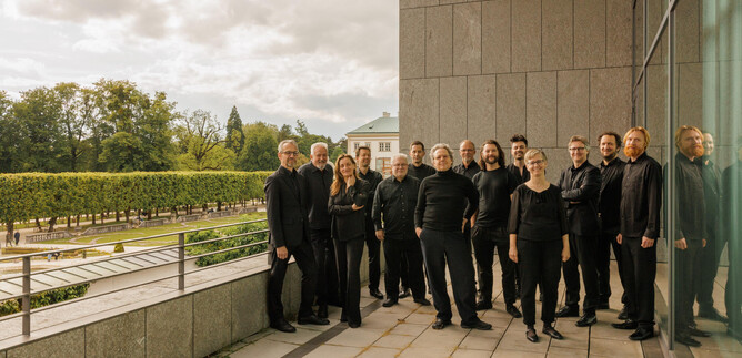 Eine Gruppe von Menschen in schwarzer Kleidung steht vor einem modernen Gebäude. Im Hintergrund sind Bäume und ein Garten sichtbar. | © Florian Voggeneder