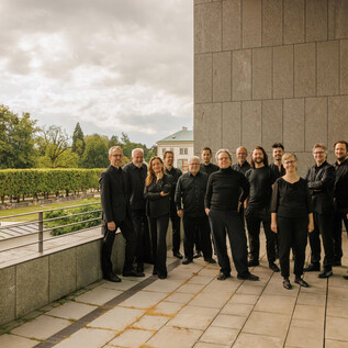 Eine Gruppe von Menschen in schwarzer Kleidung steht vor einem modernen Gebäude. Im Hintergrund sind Bäume und ein Garten sichtbar. | © Florian Voggeneder