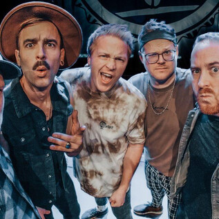 A group of five men poses for a selfie on a stage. They display various facial expressions and wear fashionable clothing. | © Barracuda Music GmbH