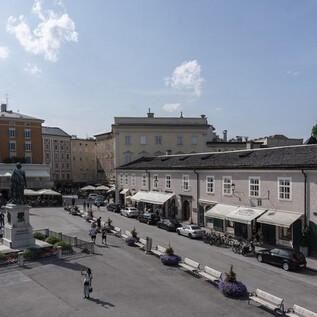 A bustling square with historic buildings and a statue in the middle. People are strolling around and enjoying the atmosphere. | © Stadtgalerie