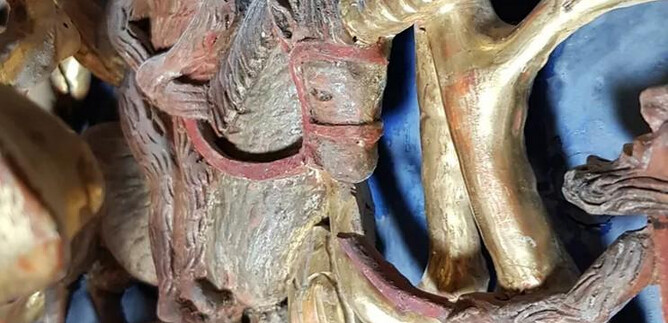 Eine kunstvolle Holzschnitzerei zeigt eine Figur auf einem Einhorn. Der Hintergrund ist in blauen und goldenen Tönen gehalten. | © Salzburger Burgen und Schlösser