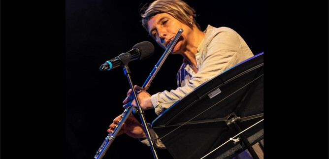 Eine Musikerin spielt Flöte auf der Bühne. Sie steht vor einem Mikrofon und konzentriert sich auf ihr Spiel. | © Hans Eder