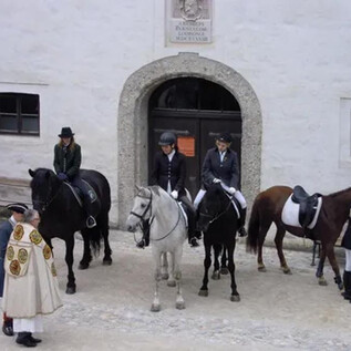 Skupina jezdců stojí před historickou budovou. Jezdí na různých koních, včetně šedého a hnědého. | © Salzburg Burgen & Schlösser