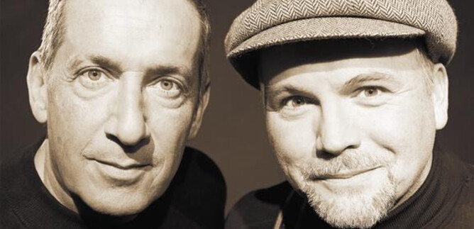 Two men pose closely together in a black-and-white portrait. They have friendly facial expressions and are wearing casual clothing. | © Lukas Beck