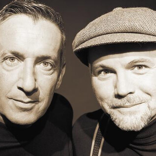 Zwei Männer posieren eng zusammen in einem Schwarz-Weiß-Porträt. Sie haben freundliche Gesichtsausdrücke und tragen lässige Kleidung. | © Lukas Beck