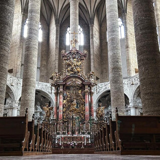 Ein beeindruckendes Kircheninnere mit hohen Säulen und aufwändigen Verzierungen. Der Altar im Mittelpunkt zieht die Blicke auf sich. | © TSG_B. Brunauer