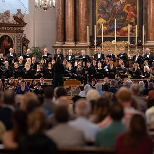 A choir sings in a church in front of a large audience. The atmosphere is festive and the participants are focused. | © Dom zu Salzburg