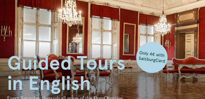 Una stanza elegante con lampadari di cristallo e grandi finestre.  
Ci sono informazioni sui tour guidati in inglese nel DomQuartier.