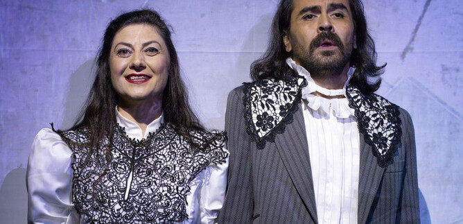 Two actors in historical costumes stand next to each other on stage. They have both cheerful and serious expressions. | © Florian Koller Mistura