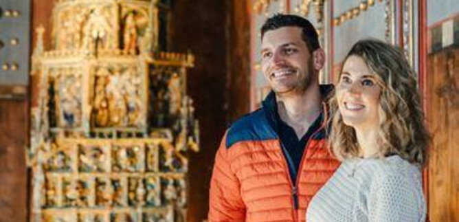 A historic kitchen with old cooking utensils and a stone fireplace. The floor is made of large stones, and there are various pots and jugs. | © Kathrin Gollackner Fotografie