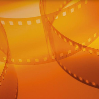 Un fondo naranja con rollos de película que se superponen elegantemente. La escena transmite una sensación de creatividad y arte cinematográfico. | © Shutterstock_Serhii Yushkov