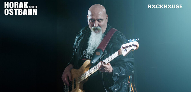 A musician is playing bass on stage. He is wearing a leather jacket and has a long white beard. | © Rockhouse Salzburg
