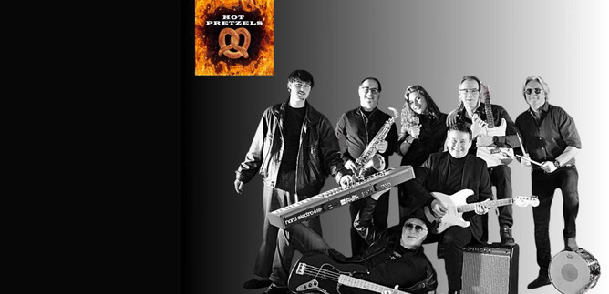 A band stands together and poses for a photo. They hold musical instruments and wear black clothing. | © Rockhouse Salzburg