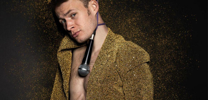 A young man is wearing a glittering suit and holding a microphone in his hand. The background is adorned with golden glitter. | © Yuting Tseng