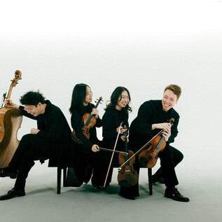 Un gruppo di quattro musicisti è seduto vestito di nero. Suonano diversi strumenti ad arco e sembrano felici. | © Co Merz