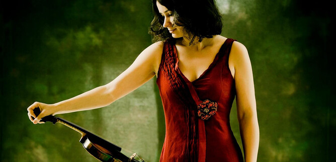 Žena v červených šatech drží v ruce housle. Pozadí je zelené a rozostřené. | © Marco Borggreve