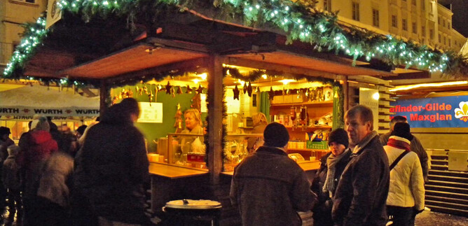 Oslňující stánek na vánočním trhu. Lidé stojí spolu a užívají si atmosféru a nabídku. | © LionsClub