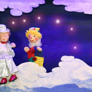 Dvě barevné panenky sedí v krajinném oblaku. Pozadí je tmavé s třpytícími se hvězdami. | © Friedburger Puppenbühne