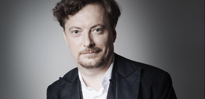 A man in an elegant suit with a white shirt and a white pocket square. The background is gray and neutral. | © Anita Schmid