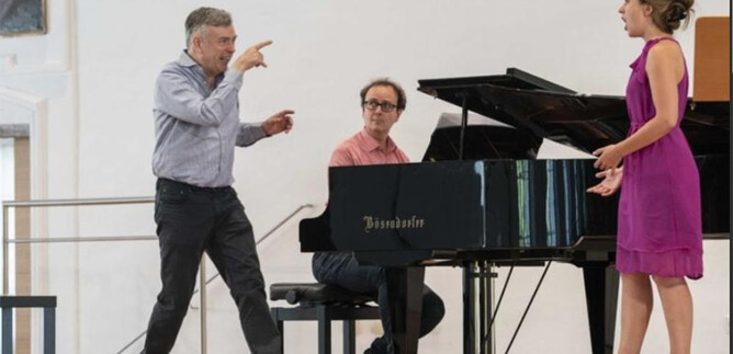 A singer is rehearsing on stage while a pianist accompanies. A man is giving instructions and is treating the event with enthusiasm. | © Salzburger Festspiele_Marco Borrelli
