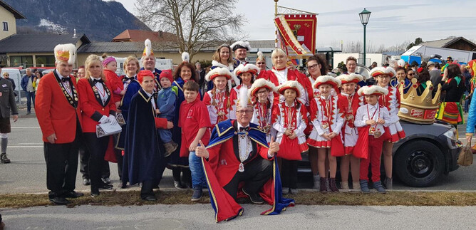 Eine Gruppe von Menschen in festlicher Kleidung steht vor einem Wagen. Sie feiern einen Umzug und wirken fröhlich. | © Salzburger Faschingsgilde