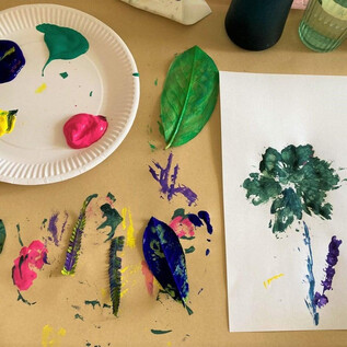 Une surface de peinture avec des couleurs vives et une feuille. Dessus, il y a une image peinte d'un arbre. | © DomQuartier