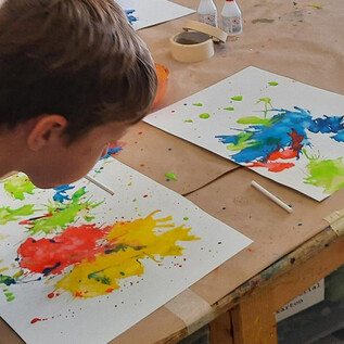 Une collection de crayons de couleur et de ciseaux dans des contenants en métal. Au premier plan, des bols orange sont visibles. | © DomQuartier